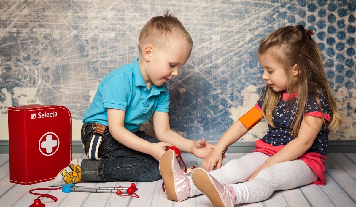 Deux enfants jouent joyeusement au docteur avec une trousse médicale jouet, incarnant l'esprit de jouer avec les tout-petits.