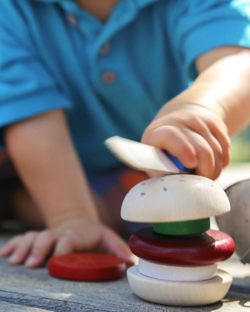 Enfant avec un burger jouet en bois de Selecta