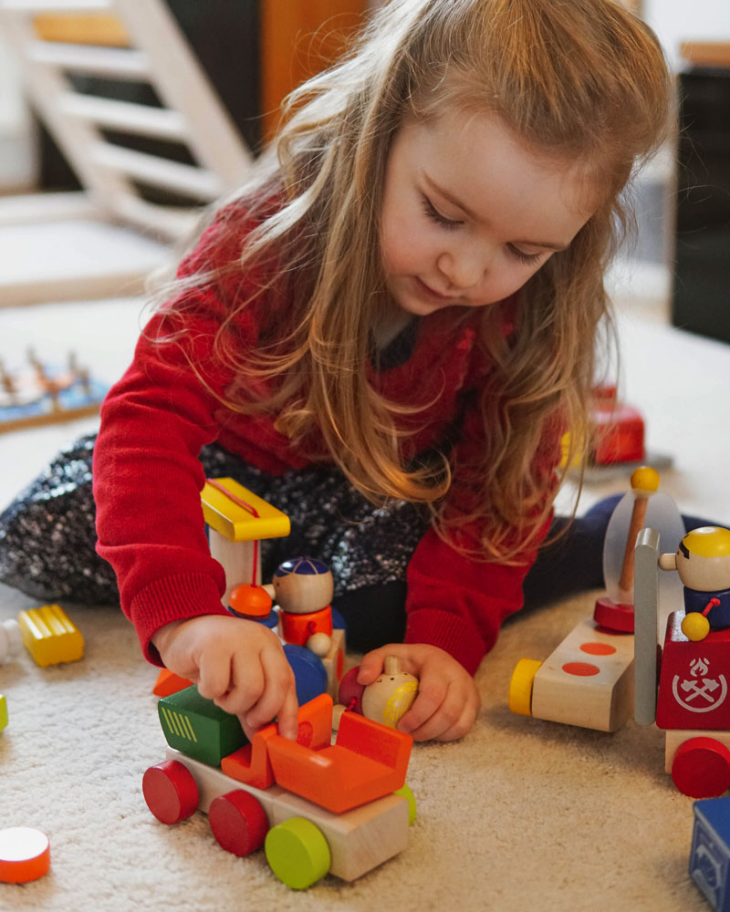 Enfant avec jouets en bois de la ferme par Selecta